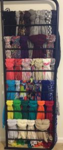 A rack of different colored scarves hanging on the wall.