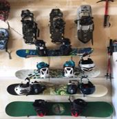A wall of snowboards and helmets on the floor.