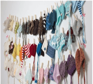 A wall of hats hanging on clothes pins.
